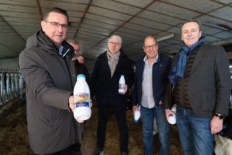 Quatre homme dans une étable, avec une bouteille de lait dans la main.