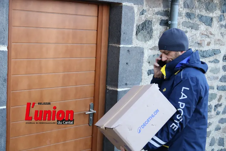 Le facteur avec un colis devant une porte en bois. 