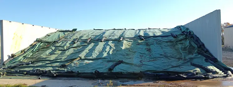 Une bâche verte est posée entre des murs en béton.