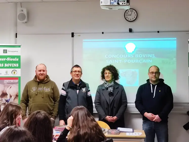 quatre personnes devant un tableau blanc dans une salle de classe