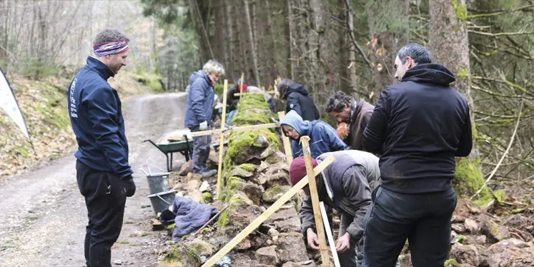 Un groupe de personne travaille sur un mur en pierre sèche