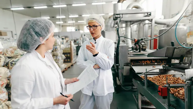 Deux employées discutent dans un laboratoire d'une entreprise agroalimentaire.