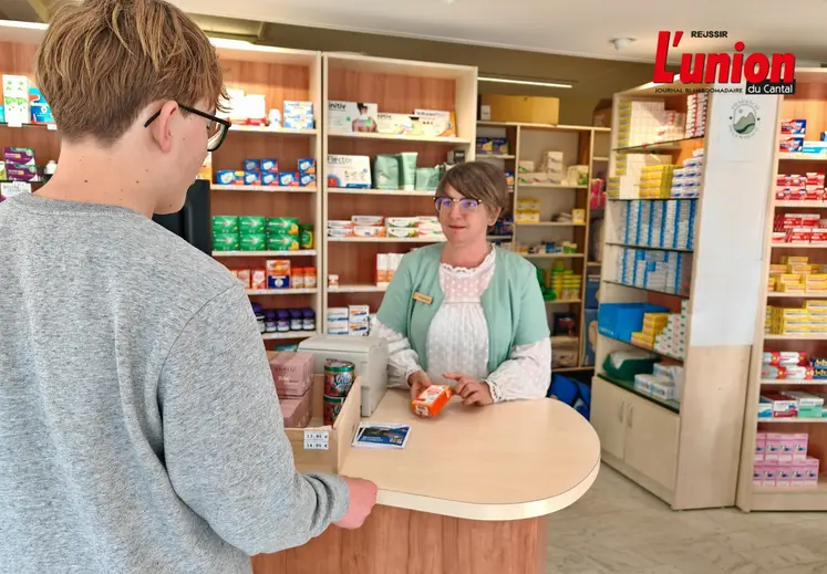 Dans une pharmacie, un patient se fait servir par une préparatrice une boîte de médicaments.