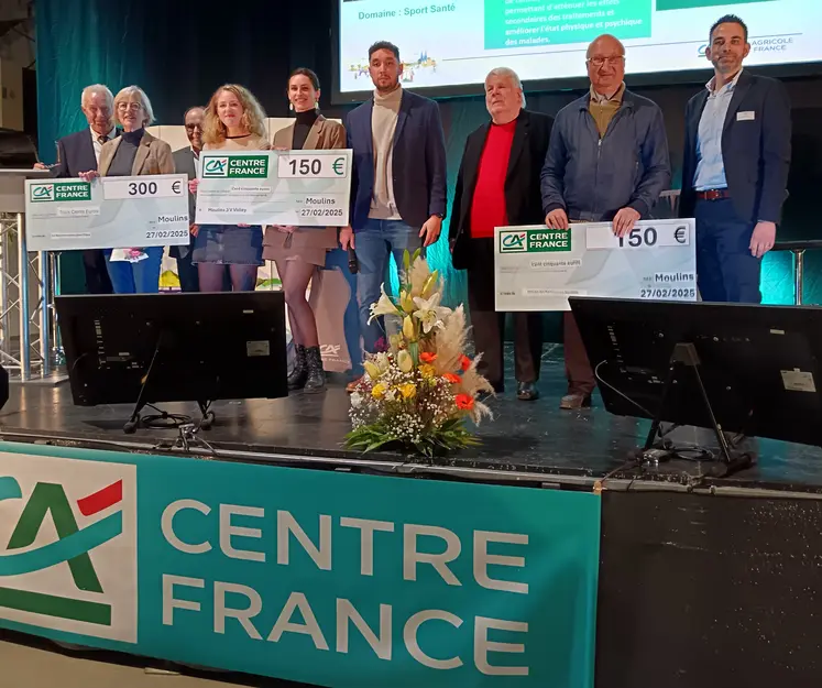 des gens sur un podium posent avec un chèque en main