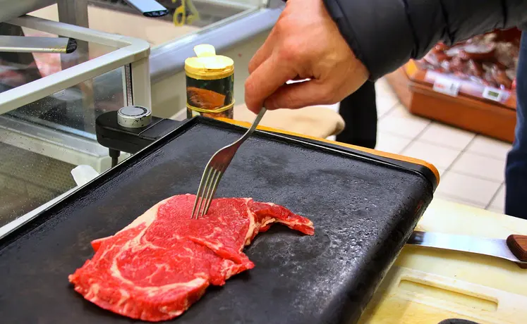 une pièce de boeuf sur une plancha, prête à être retournée à la fourchette