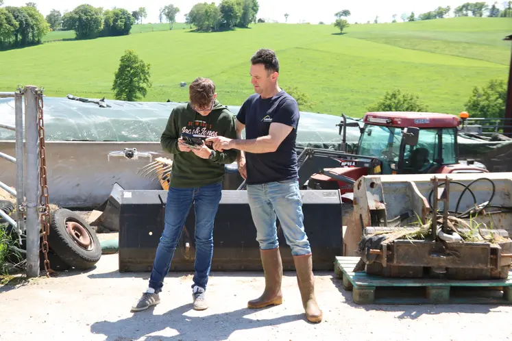 Deux hommes devant un silo de ferme faisant décoller un drone