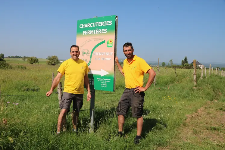 Deux hommes devant un panneau de promotion d'une exploitation agricole.