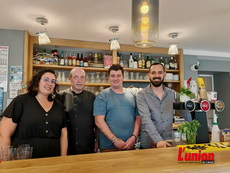Quatre personnes derrière un comptoir de bar. 