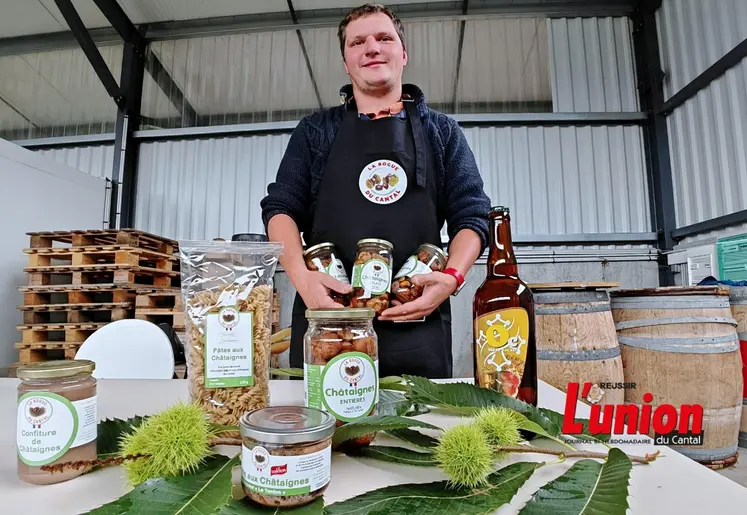 Un homme en tablier noir présente une gamme de produits transformés à base de châtaignes.