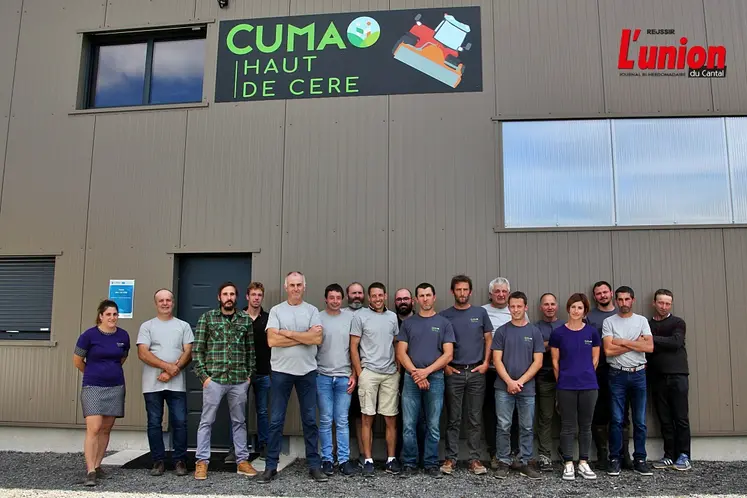 un groupe d'agriculteurs devant le pignon d'un bâtiment agricole avec le logo d'une Cuma