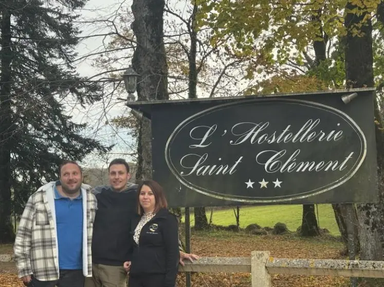 Deux hommes et une femme devant le panneau de l'hostellerie