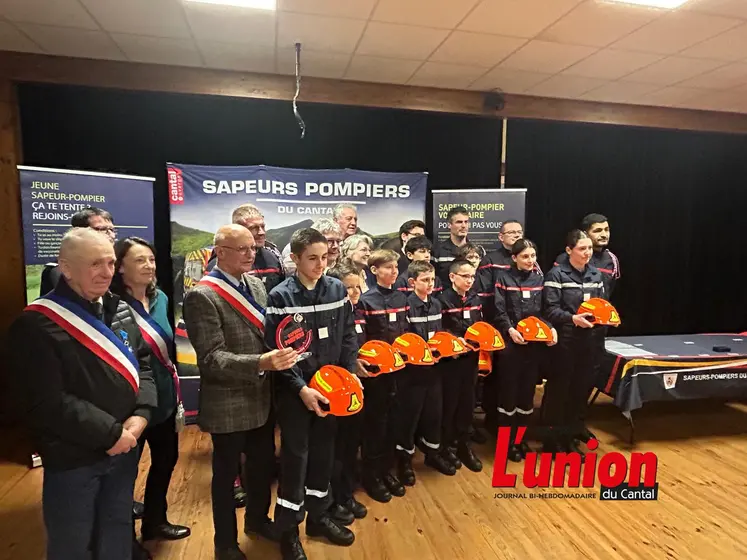 Les élus en écharpes tricolores entourent les jeunes sapeurs-pompiers avec leurs casques à a main.