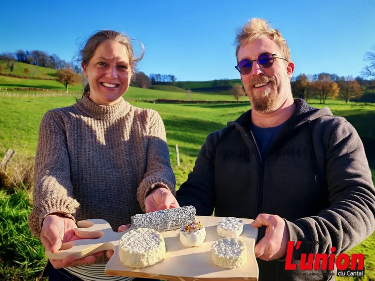 Un couple présente un plateau de fromages de chèvres, dans un paysage de campagne