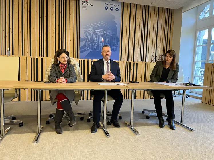 Trois personnes présentent un bilan à une table dans une salle de préfecture