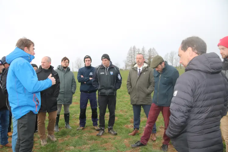 Groupe de personnes au milieu d'un pré où des monticules de terre sont visibles.