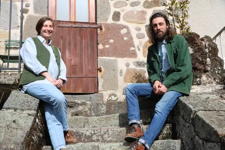 Une jeune femme et un jeune homme posant, assis sur les escaliers d'une vieille maison en pierre