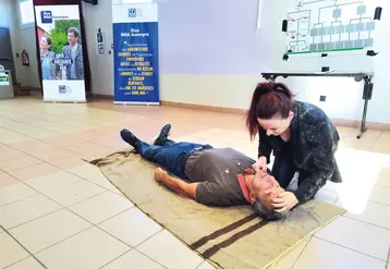 Une femme montre comment positionner la tête d'une personne inconsciente sur le sol, pour lui faire du bouche à bouche.