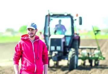 Jeune agriculteur dans un champ devant un tracteur