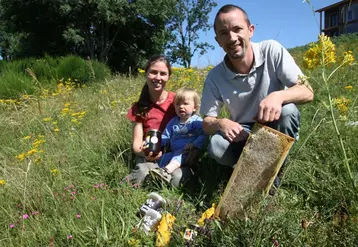 Emmanuel et Véronique avec l'un de leur deux fils sur une parcelle de prairie fleurie.