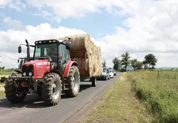 Tracteurs et remorques de fourrages circulant sur une route.