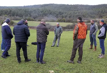 Un groupe d'hommes discute en rond au milieu d'une parcelle agricole.