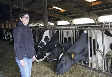 L'agricultrice Anne-Laure Fraisse sourit aux côtés de son troupeau de Prim'Holstein en train de manger.