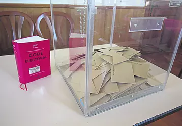 Code électoral et urne dans un bureau de vote.