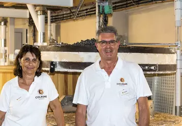 Chantal Rech et Jean-Pierre Constans, les co-directeurs du moulin de Colagne devant la meule de pierre en silex.