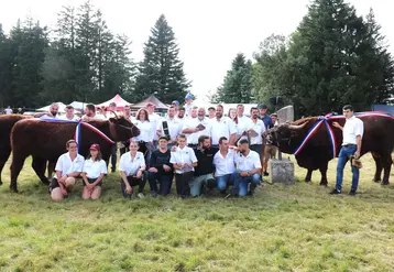 Un groupe de gens habillés en blanc posent à côté de vaches salers lors d'un concours