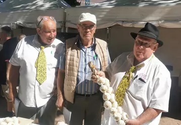 Trois hommes âgés, l'un deux tient une tresse d'ail