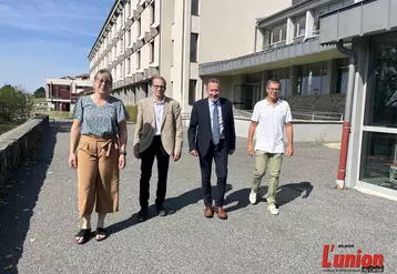 Quatre personnes, une femme et trois hommes marchant de face devant un lycée