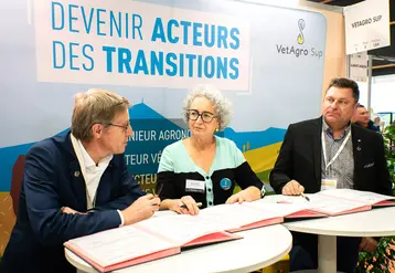Deux hommes et une femmes assis à des table, des documents à signer devant eux