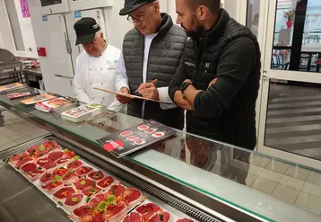 3 hommes observent et jugent des pavés de bœuf découpés par des apprentis bouchers.