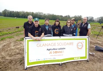 Un groupe se tenant derrière une banderolle "glanage solidaire" au milieu d'un champ