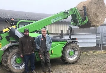 Deux hommes souriants, un jeune et un plus âgé, sont appuyés sur une machine agricole.