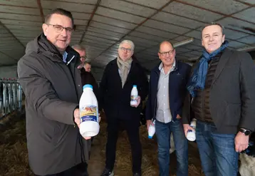 Quatre homme dans une étable, avec une bouteille de lait dans la main.