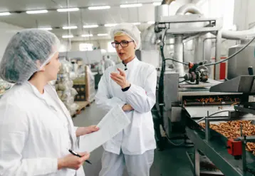 Deux employées discutent dans un laboratoire d'une entreprise agroalimentaire.