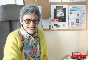 Une dame souriante assise à son bureau