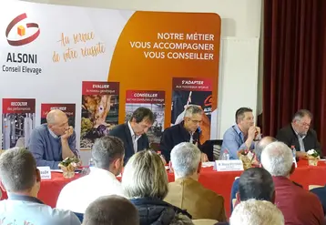 5 hommes assis derrière une table, face à une assemblée