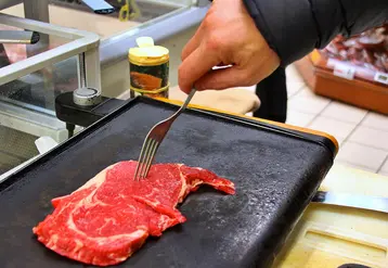une pièce de boeuf sur une plancha, prête à être retournée à la fourchette