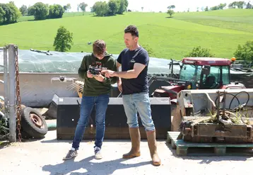 Deux hommes devant un silo de ferme faisant décoller un drone
