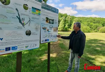 le maire du rouget devant des panneaux informatifs et un lac vide