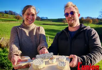 Un couple présente un plateau de fromages de chèvres, dans un paysage de campagne