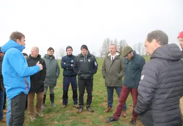 Groupe de personnes au milieu d'un pré où des monticules de terre sont visibles.