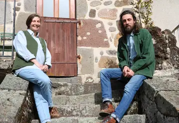Une jeune femme et un jeune homme posant, assis sur les escaliers d'une vieille maison en pierre