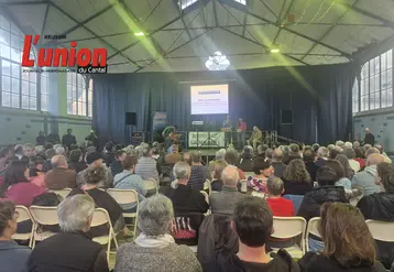 des gens de dos dans une salle avec au fond un écran lumineux