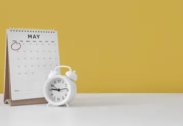 Calendrier sur une table à côté d'une horloge.
