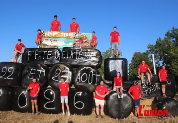 groupe de jeunes agriculteurs en maillot rouge sur un tracteur fait de ballots de foin