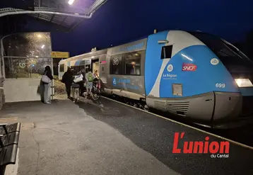 à gauche de la photo des gens montent dans un train bleu.