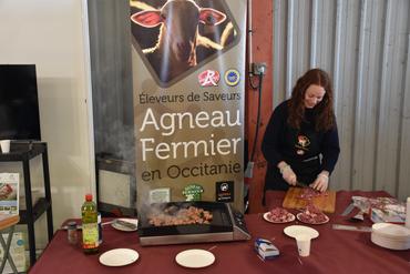 Une exposante prépare de la viande d'agneau à déguster.